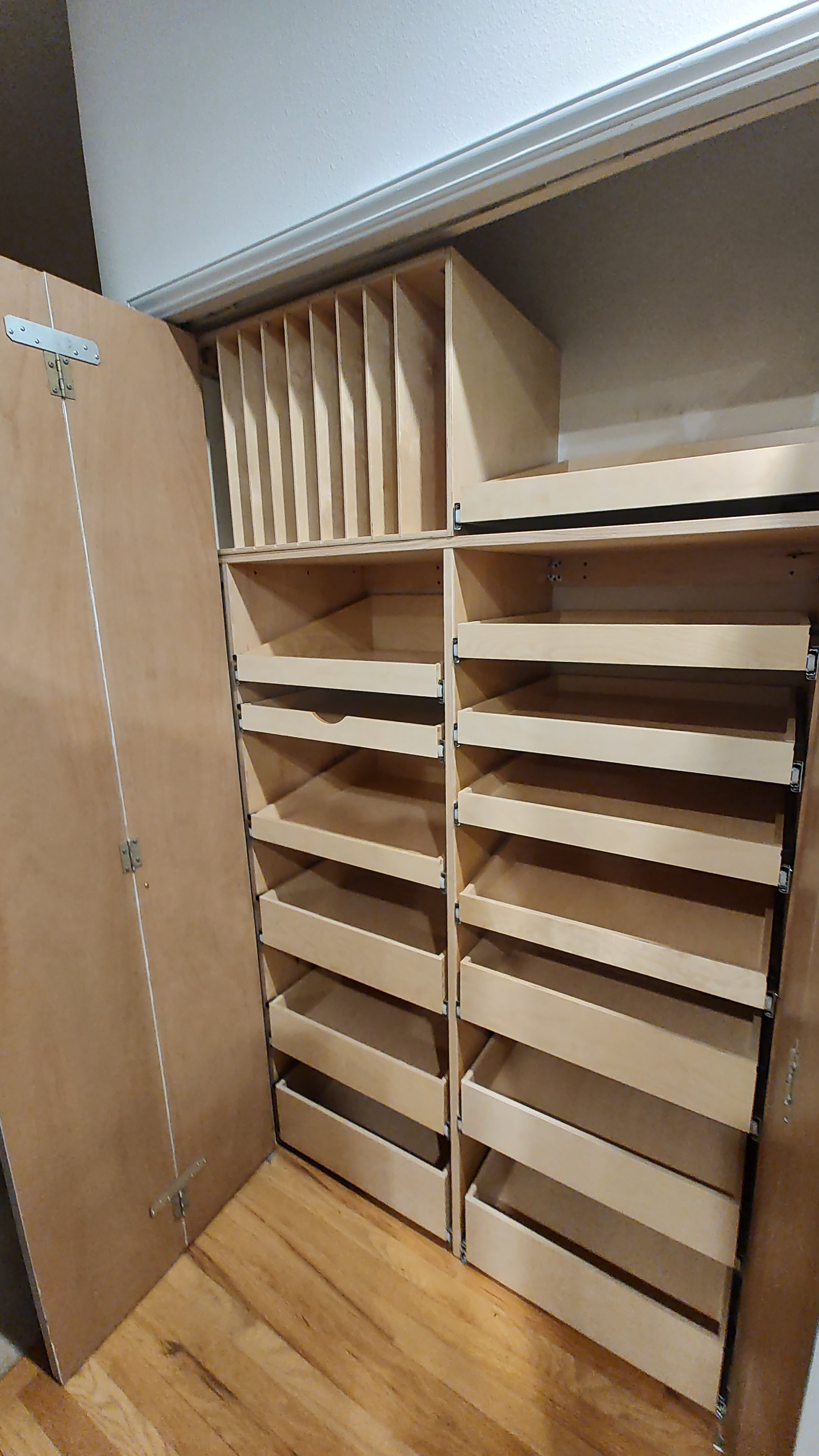 Wooden cabinet with adjustable shelves and vertical dividers inside a room.
