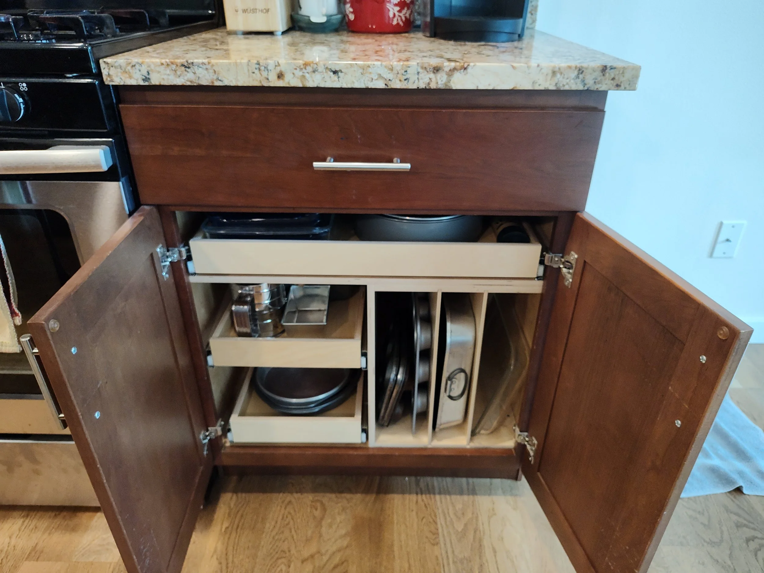 Open kitchen cabinet containing pots, pans, and kitchenware.