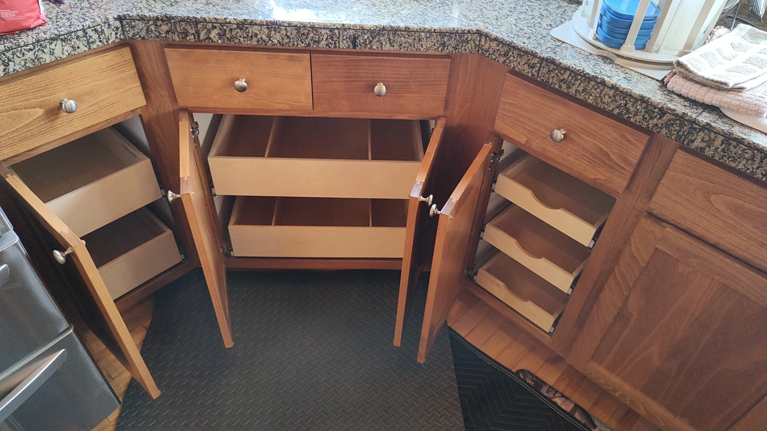 Kitchen cabinets with open doors showing empty shelves and drawers