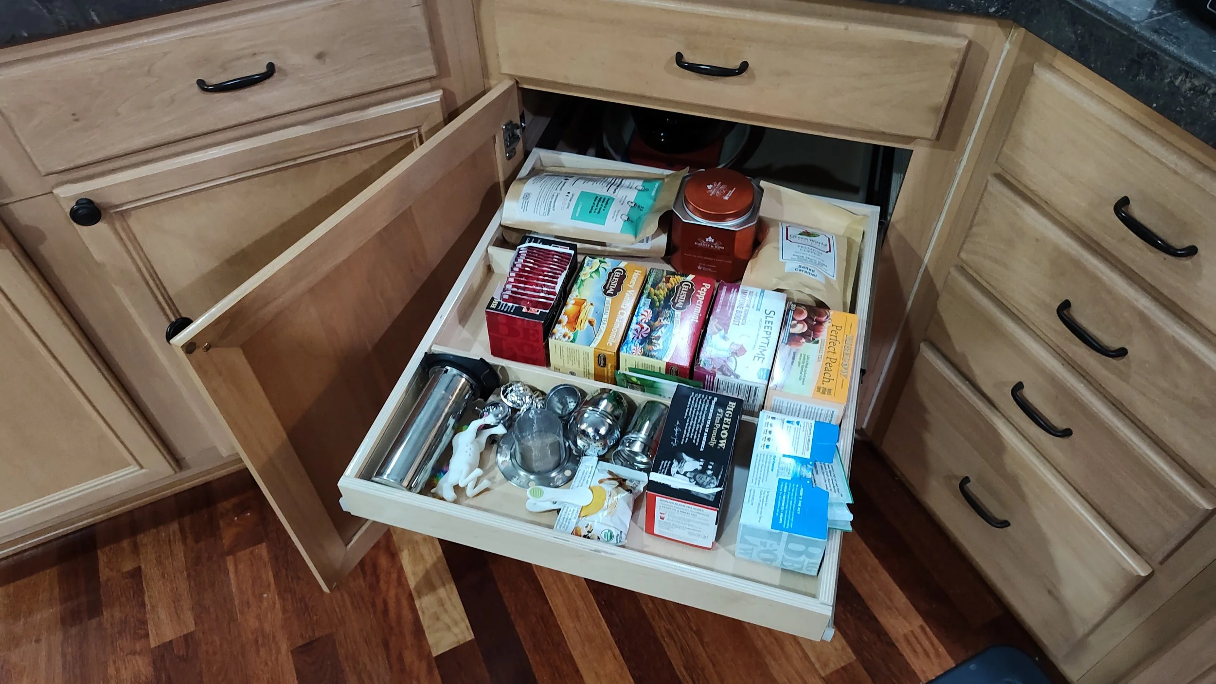 Open kitchen drawer filled with various household items, including jars, containers, and kitchen accessories.