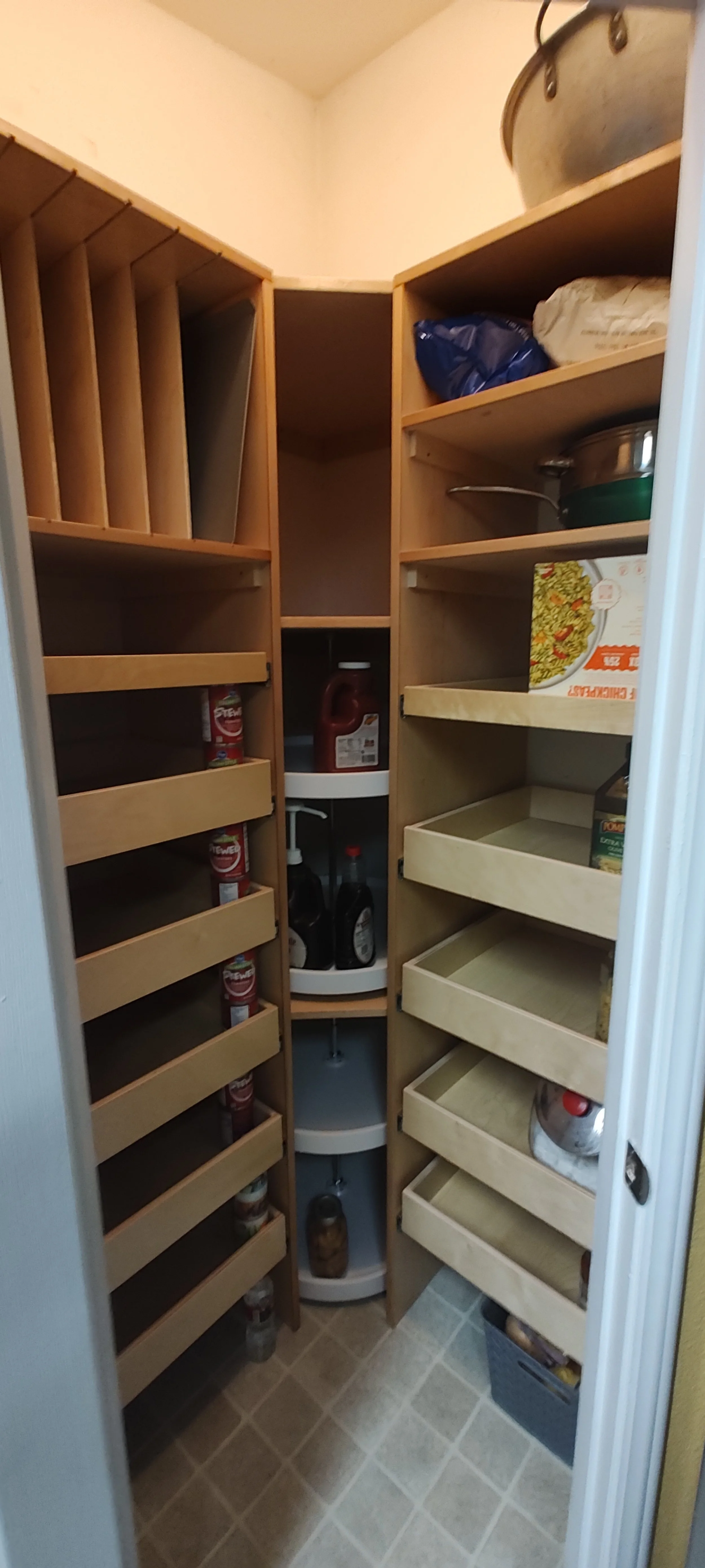 Pantry with empty shelves and a few bottles of condiments or sauces on a central corner shelf.
