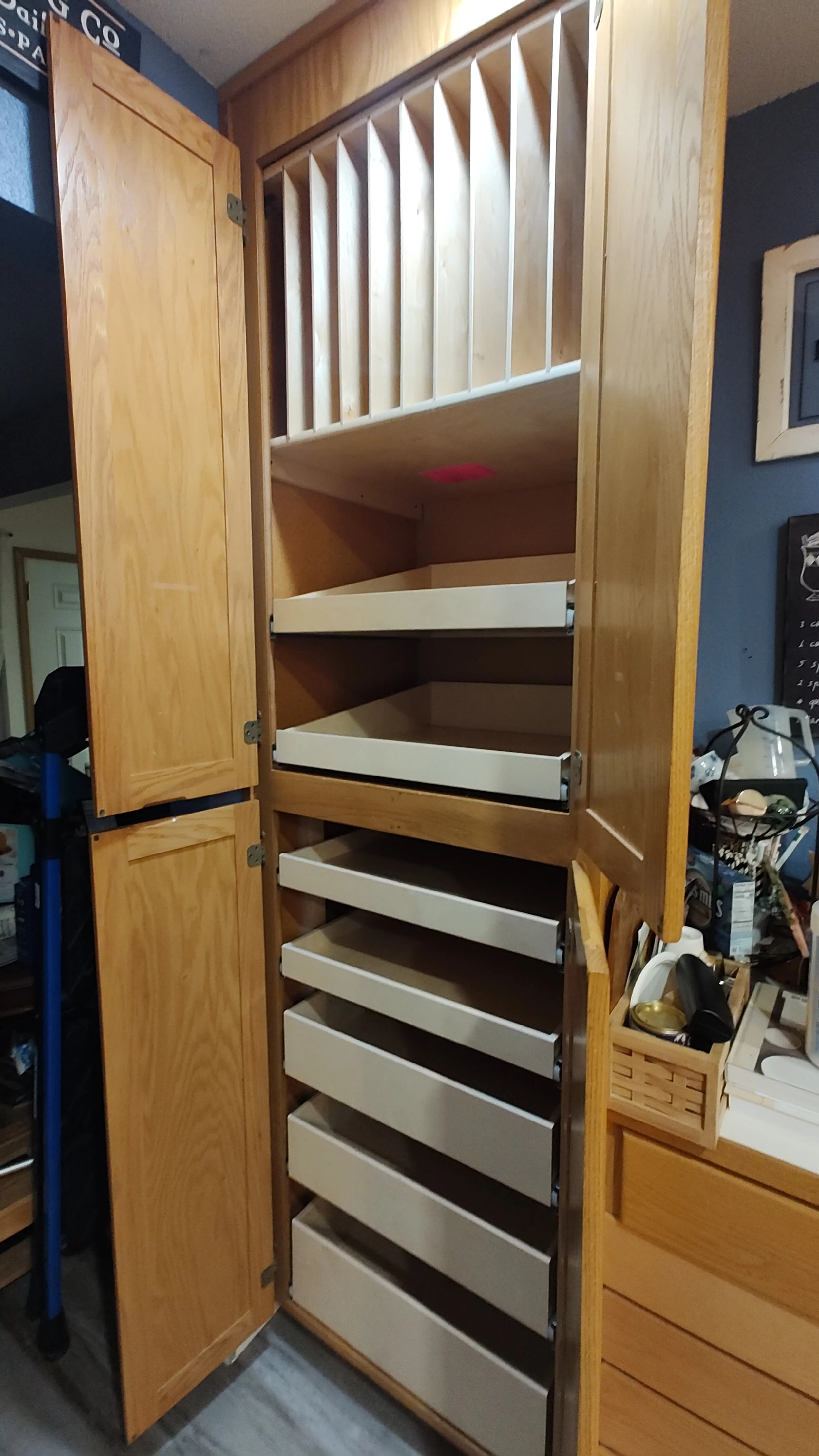 A tall wooden cabinet with open doors revealing multiple empty white and wooden open shelves and vertical slots inside.