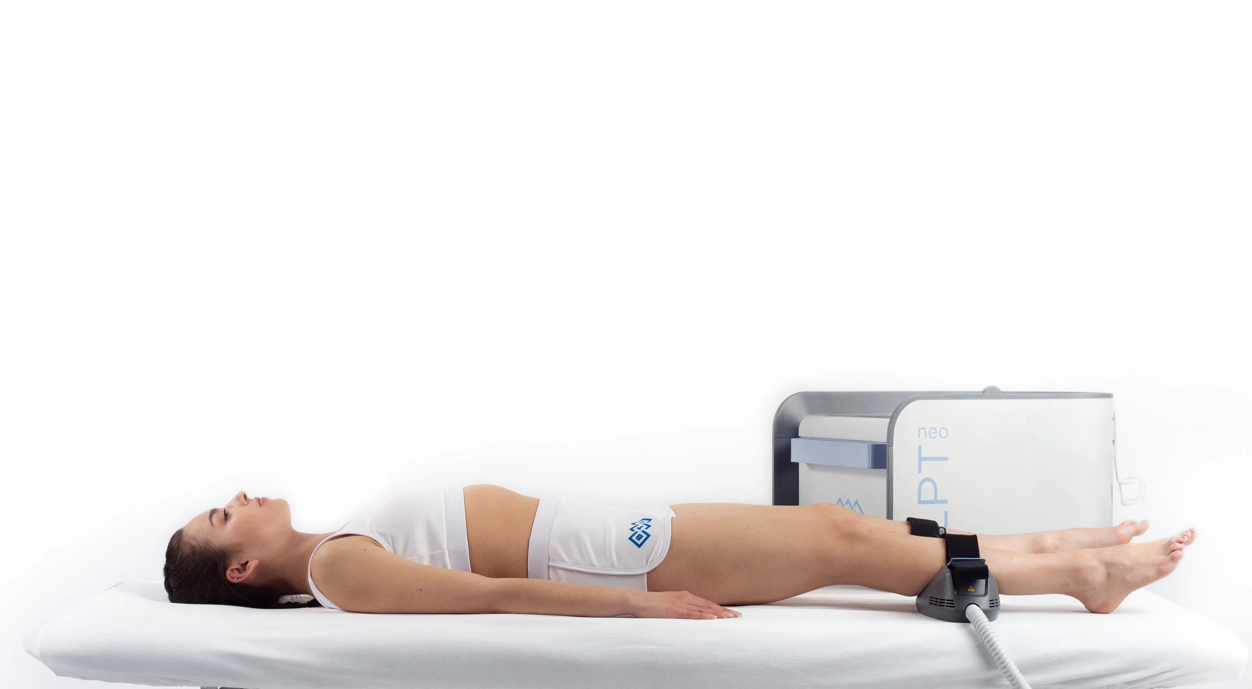 A woman with short dark hair wearing a white off-the-shoulder top, with facial therapy patches placed on her forehead, cheeks, and jawline.