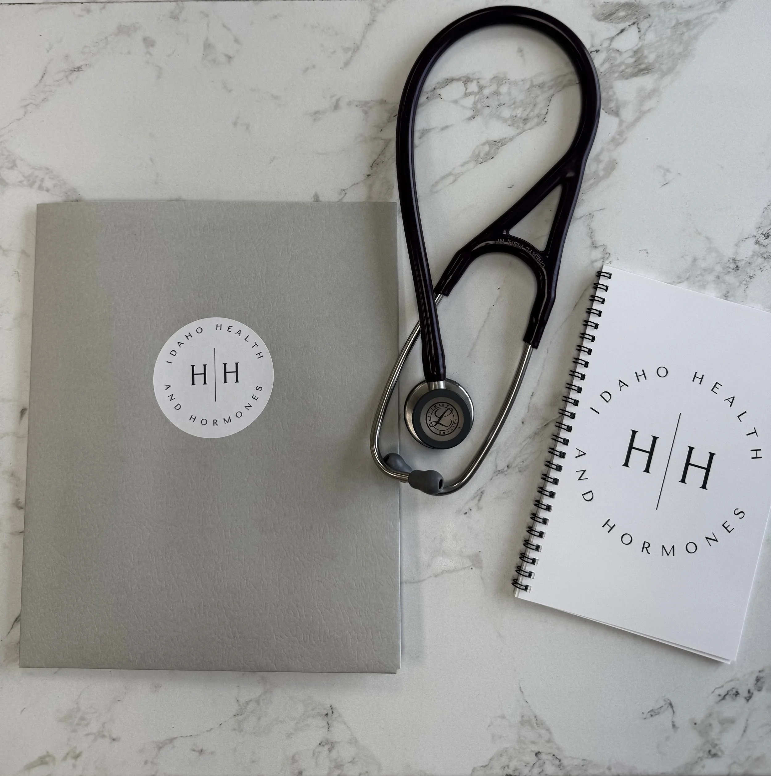 A woman with short dark hair wearing a white off-the-shoulder top, with facial therapy patches placed on her forehead, cheeks, and jawline.