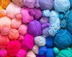 Assortment of colorful yarn balls in pink, purple, blue, and other pastel shades.