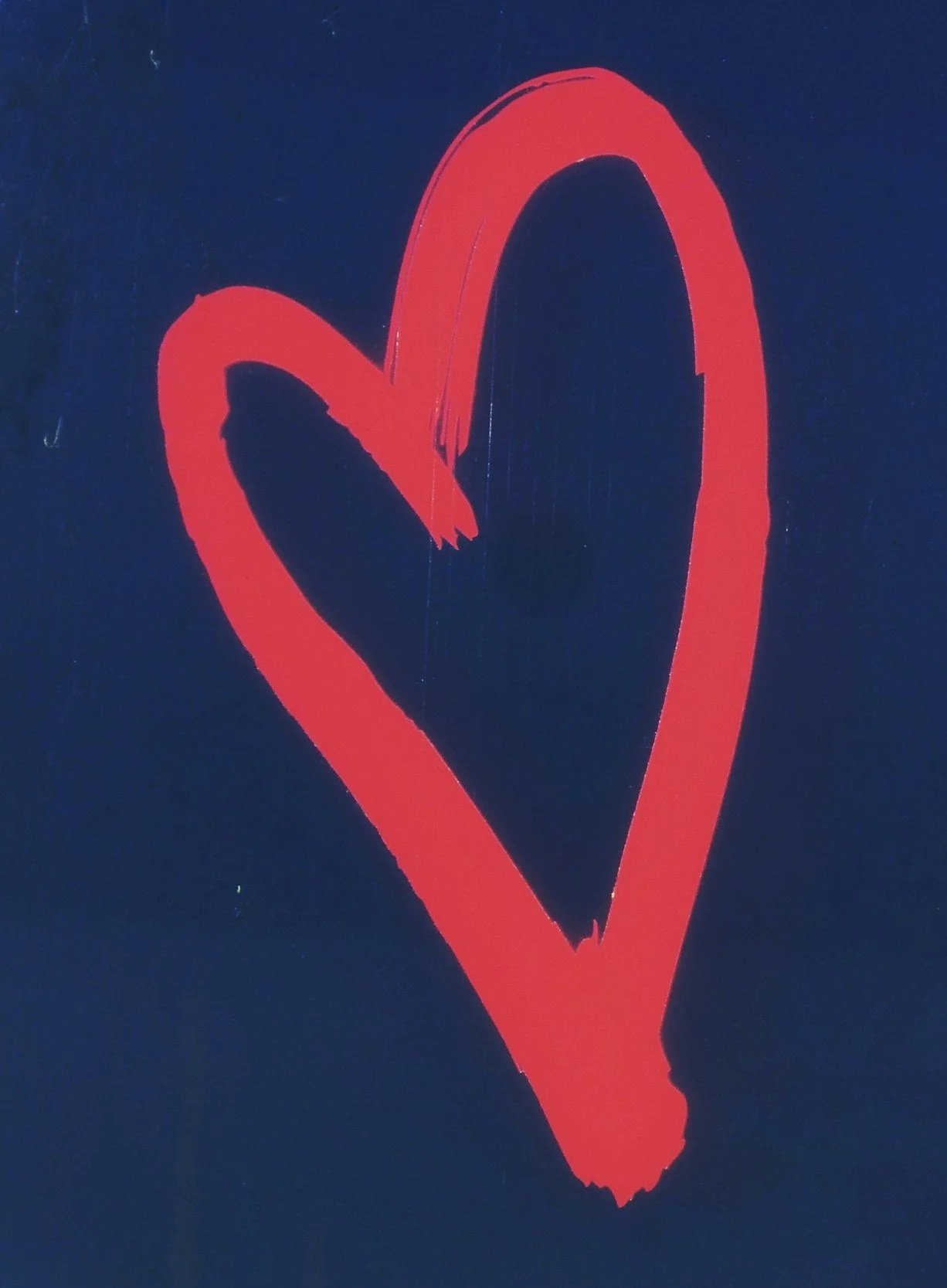 A red heart drawn with a brush on a dark blue background.
