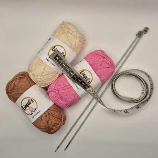 Three balls of yarn in cream, pink, and brown colors with knitting needles and a measuring tape.