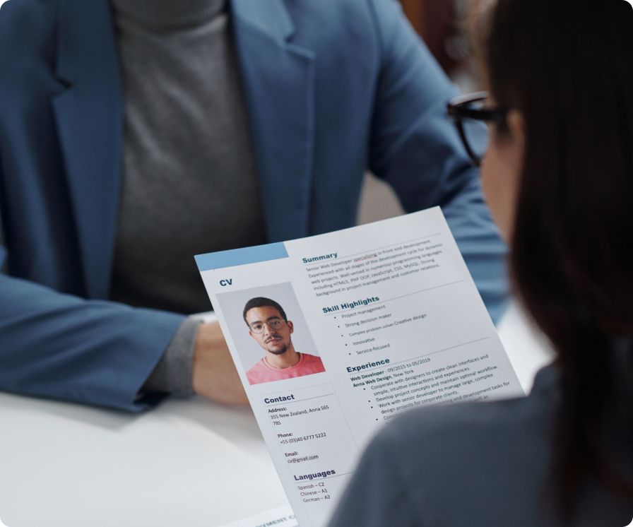 A person interviewing another person, who is holding a resume.