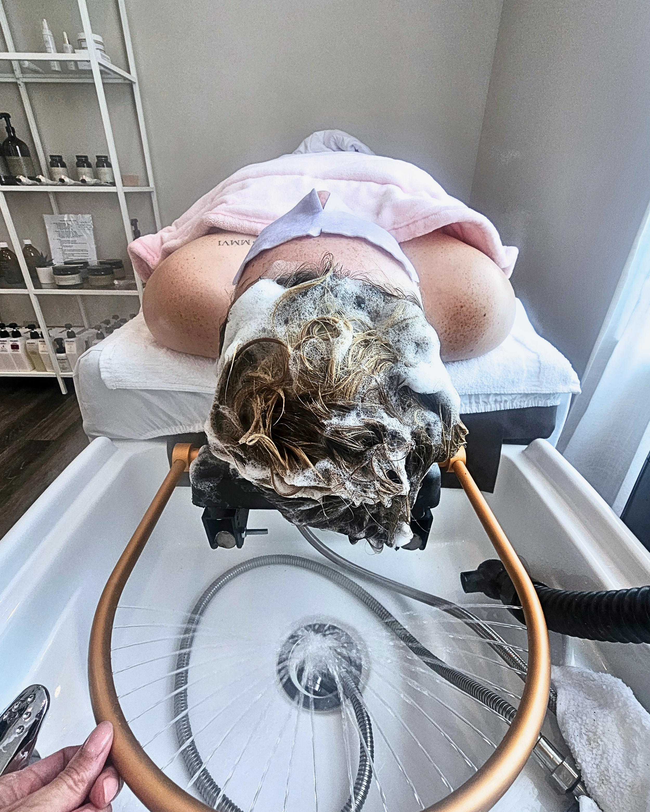 Person receiving a head spa scalp facial head massage treatment, lying down on a head spa bed.