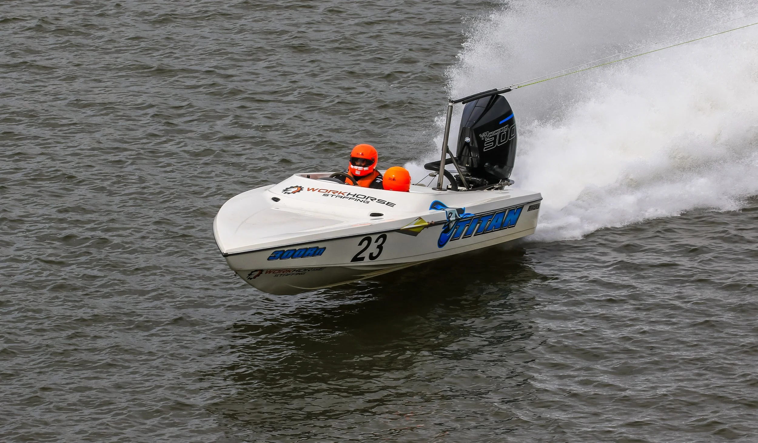 A speedboat racing on water with two people inside, both wearing orange helmets. power boat labsport raceboat
