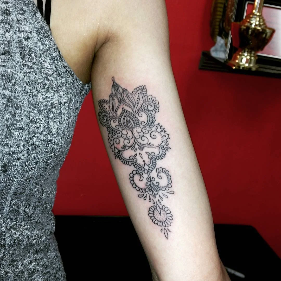 Black outline floral tattoo on person's upper arm.