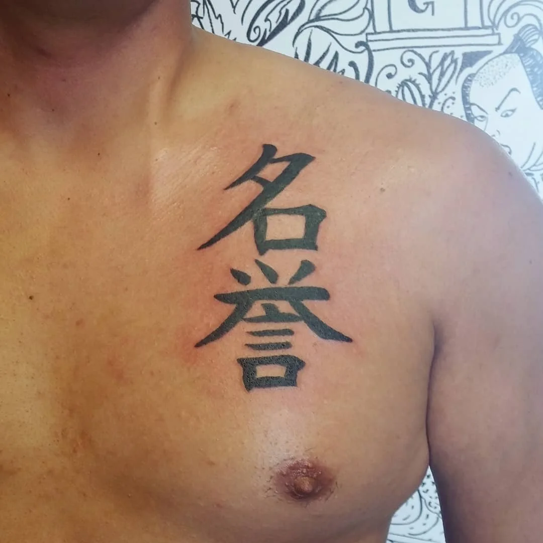 Tattoo of two large Chinese characters on a person's chest near the shoulder.