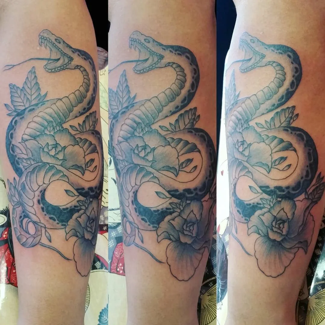 Tattoo of a snake entwined with flowers on a person's arm.