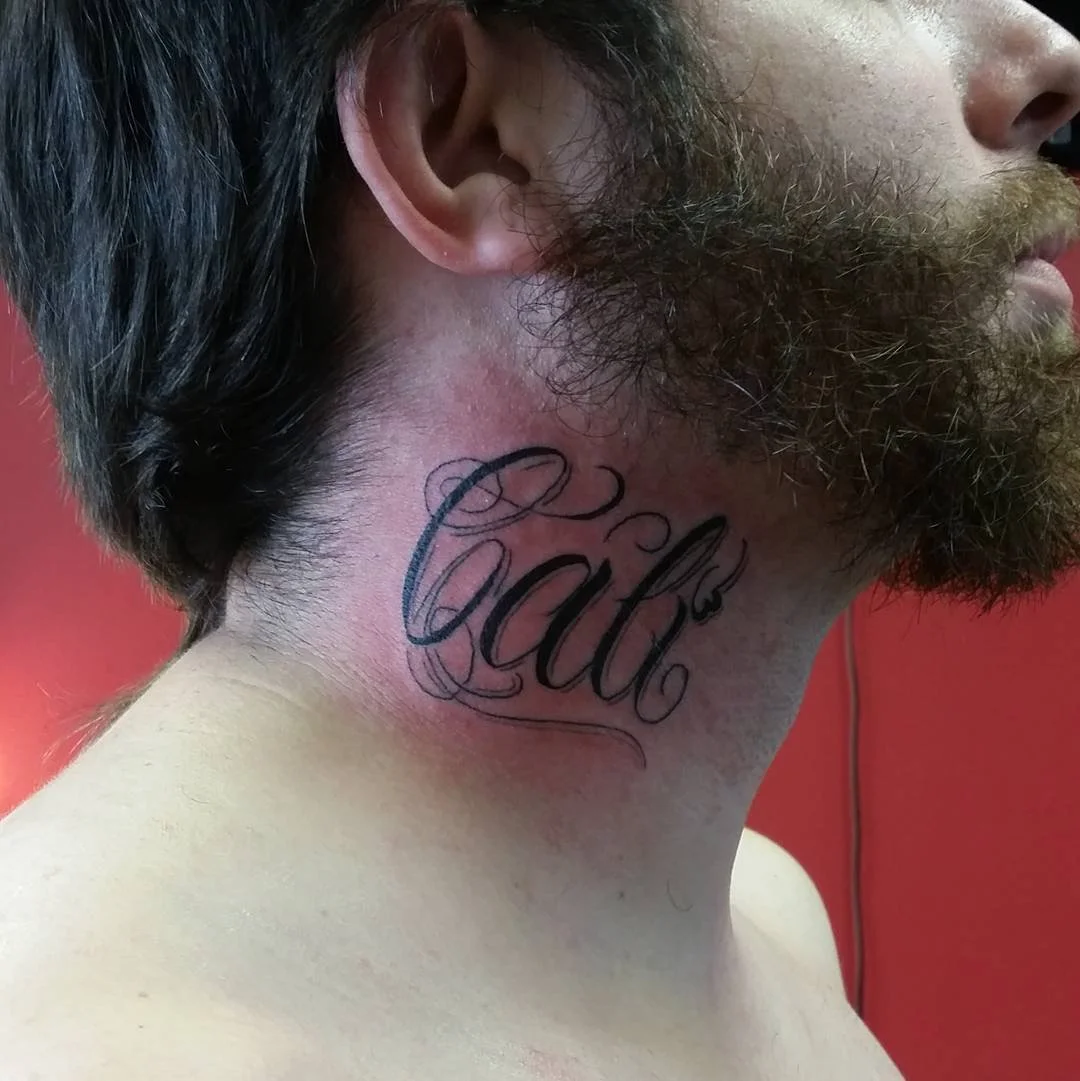 A man with a beard has a tattoo that says 'Cali' on the side of his neck.