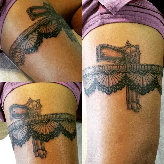 Tattoo of a revolver and lace pattern on upper thigh.