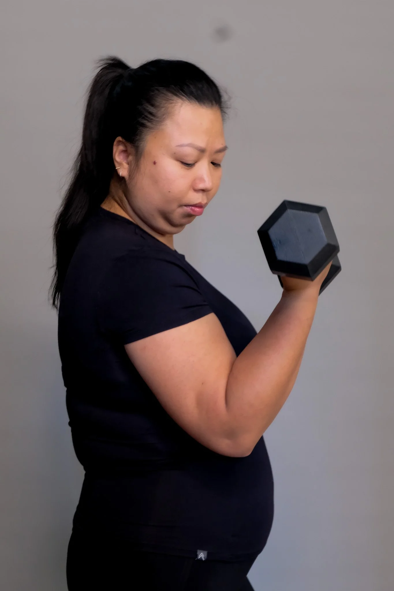 Woman lifting a black dumbbell in a workout session.