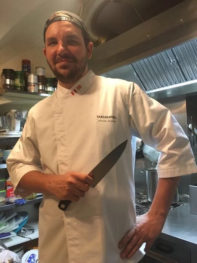 Chef en una cocina industrial sosteniendo un cuchillo.