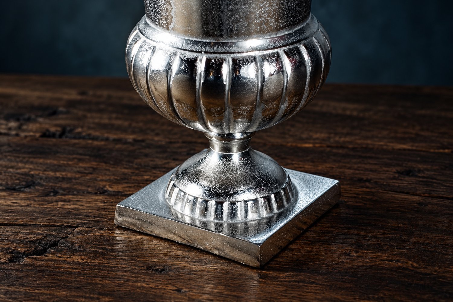Närbild av aluminiumvasens räfflade mittparti, strukturerade yta och fyrkantiga fot.