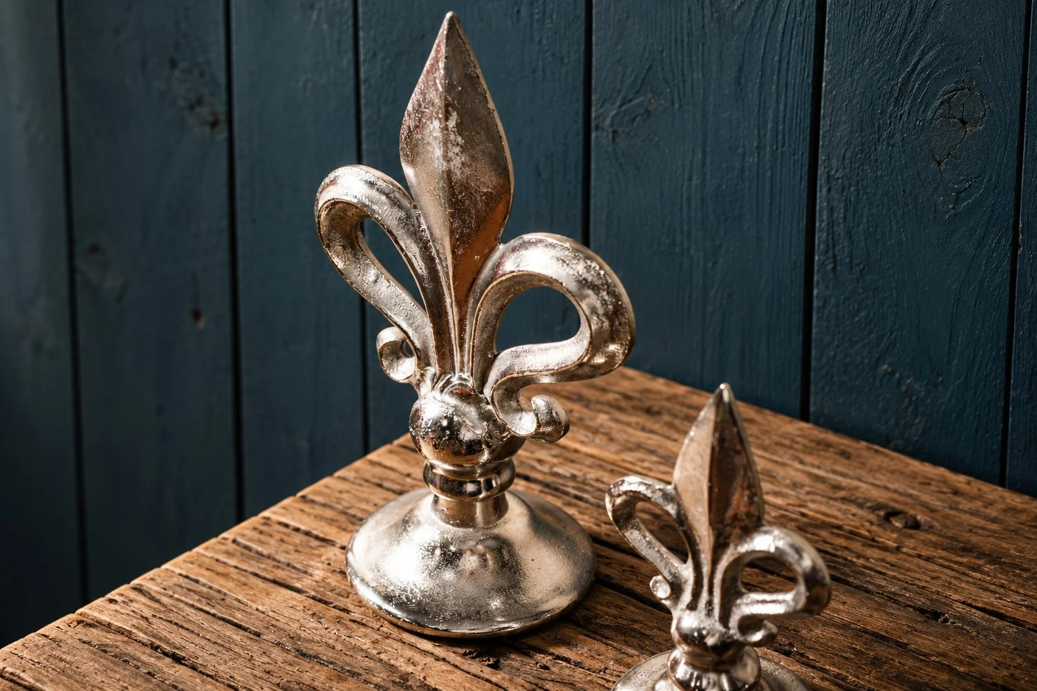 Närbild av det stora liljeornamentet i silverfärgad aluminium, med den mindre modellen till höger.