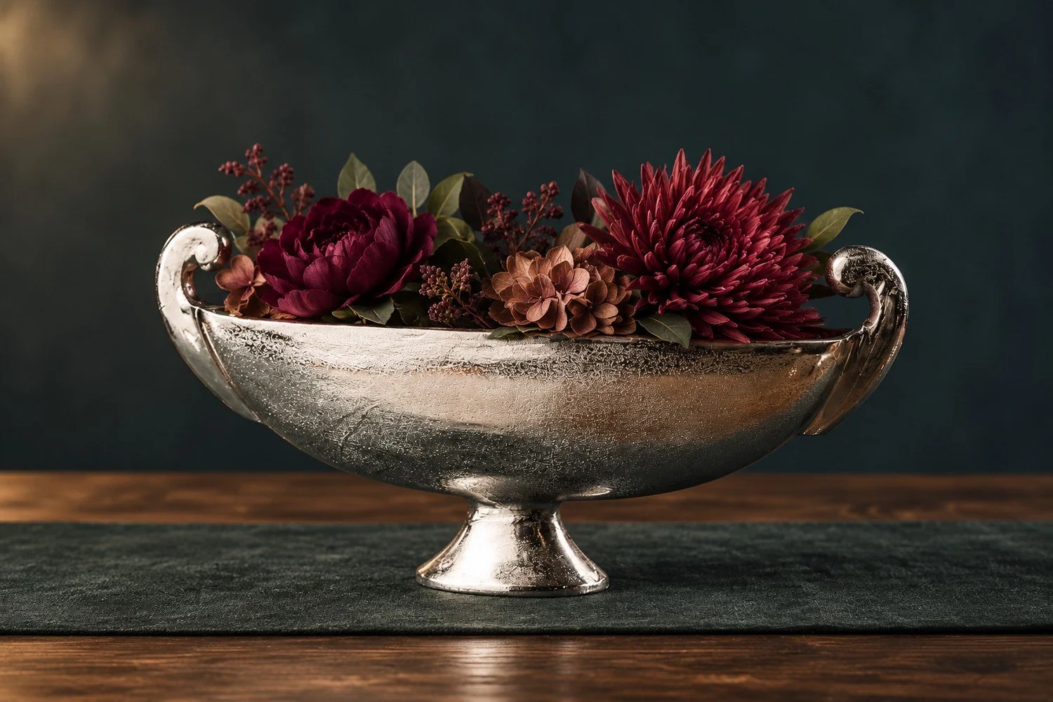 Båtformad dekorationsskål i aluminium med vinröda blommor.