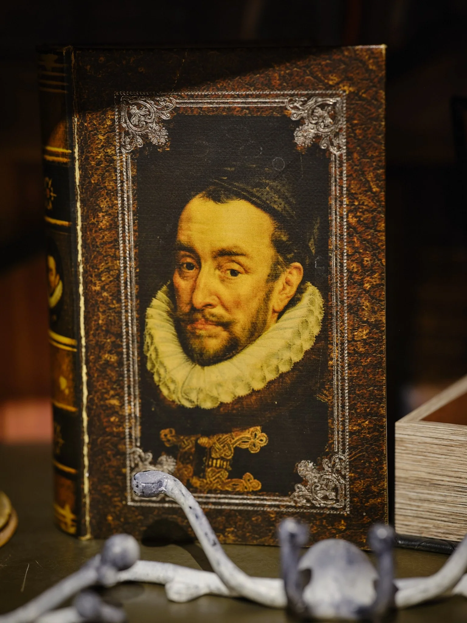 En bok med en historisk målning av en man med håret dragen bakåt, klädd i en pläd med stor vit krage