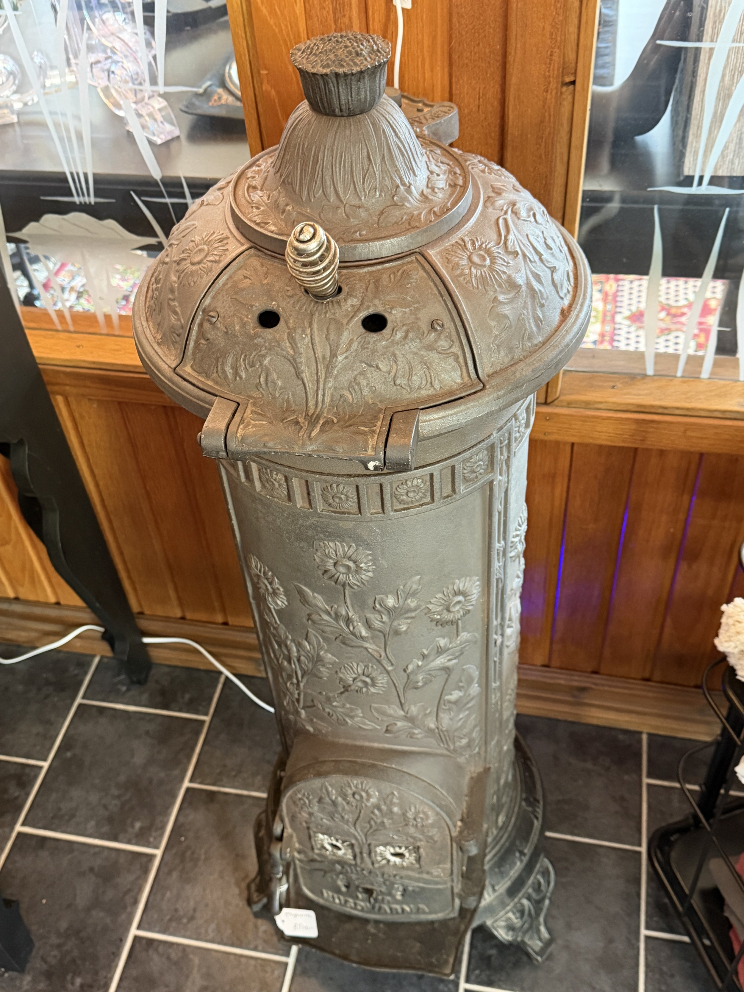 Närbild av den ornamenterade ovandelen på en antik Husqvarna gjutjärnskamin.