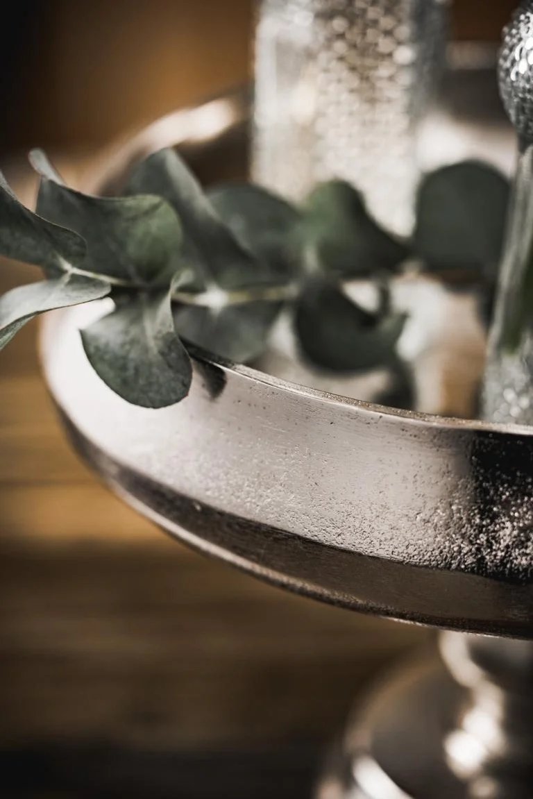 skål på fot i rå aluminium med matt silverfinish och växtdetalj