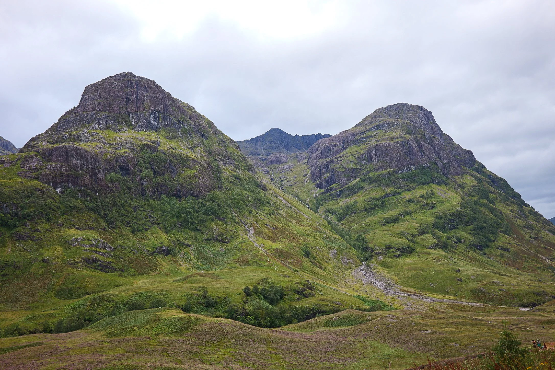 Scenic view of lush green mountains with rugged peaks under cloudy sky.