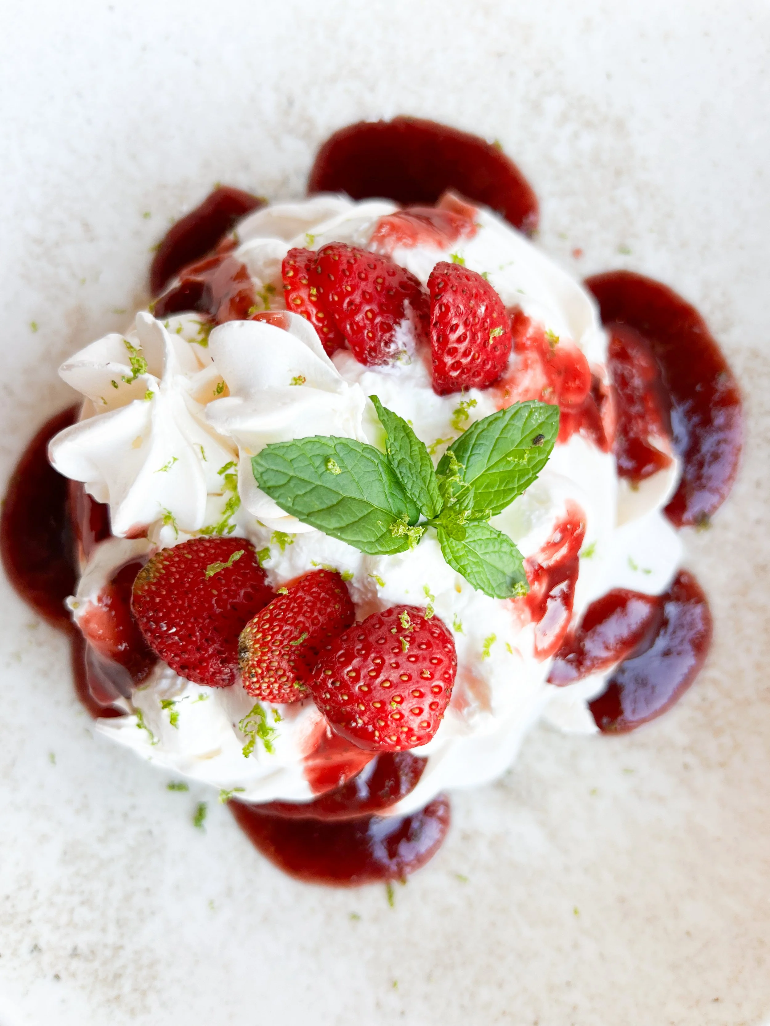 Strawberry shortcake dessert topped with whipped cream, fresh strawberries, and mint leaves