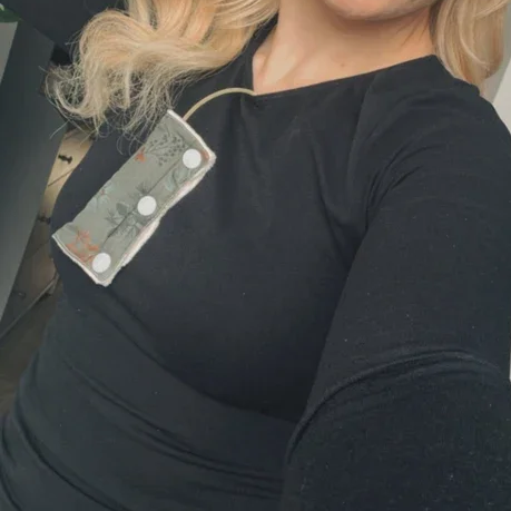 Frau trägt einen schwarzen Pullover mit einer Notfallpfeife und Geldscheine in der Nähe des Halses.