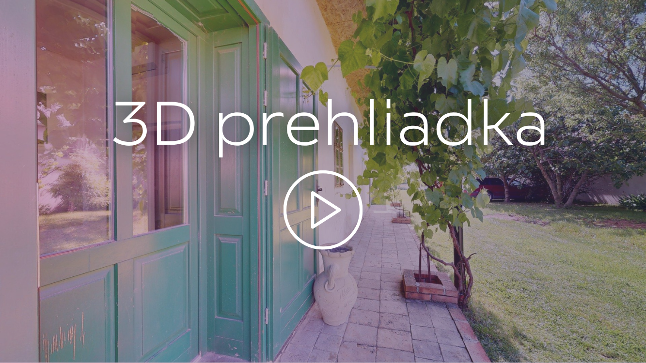 A house with a green door and multiple windows, a tiled walkway, and a flowering tree on a sunny day.
