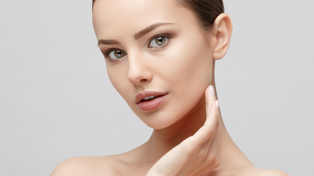 Close-up of a beautiful woman with flawless skin touching her cheek gently.