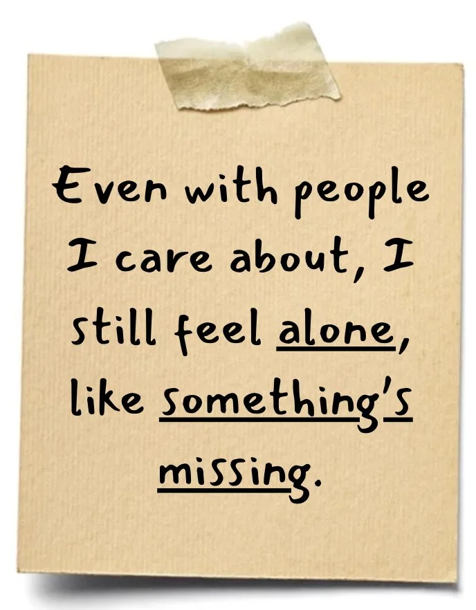 A beige sticky note with a message that says, "Even with people I care about, I still feel alone, like something's missing," taped with a piece of tape at the top.