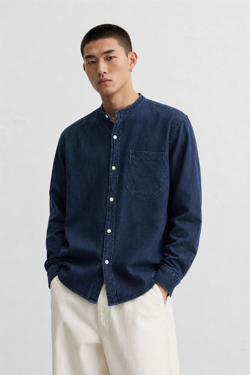 Male model wearing an Indigo by Country Road navy blue premium cotton shirt with a minimalist band collar, long sleeves, chest pocket, and clean contemporary design.