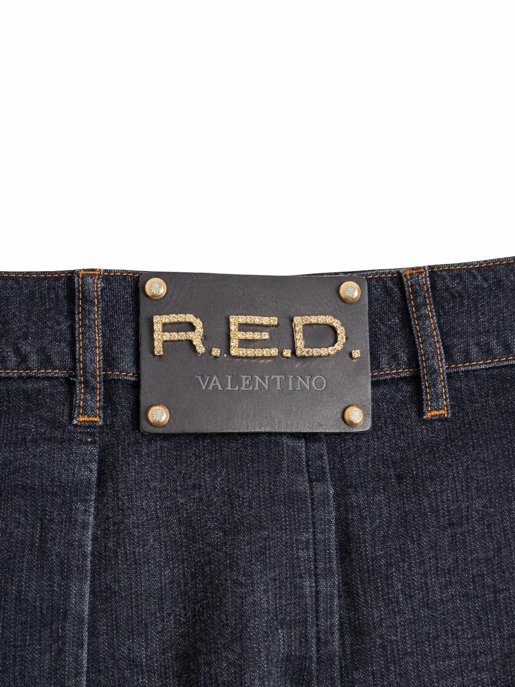 Close-up of R.E.D. Valentino logo plaque on dark denim skirt waistband