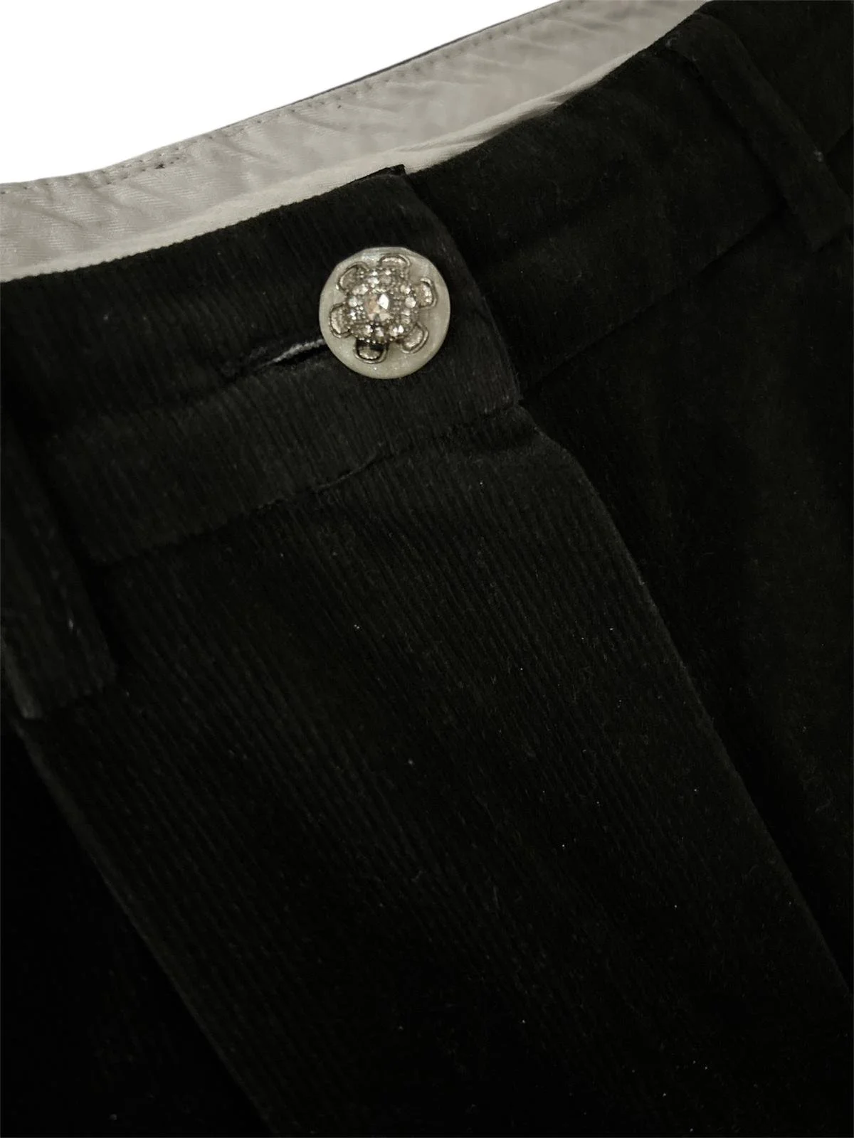 Vintage style decorative button on black velvet trousers