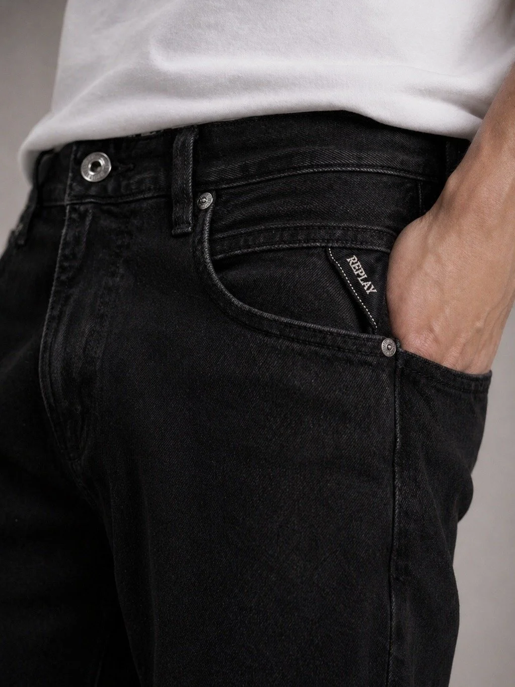Close-up of Replay men’s black slim fit jeans with signature pocket detail and dark washed denim texture