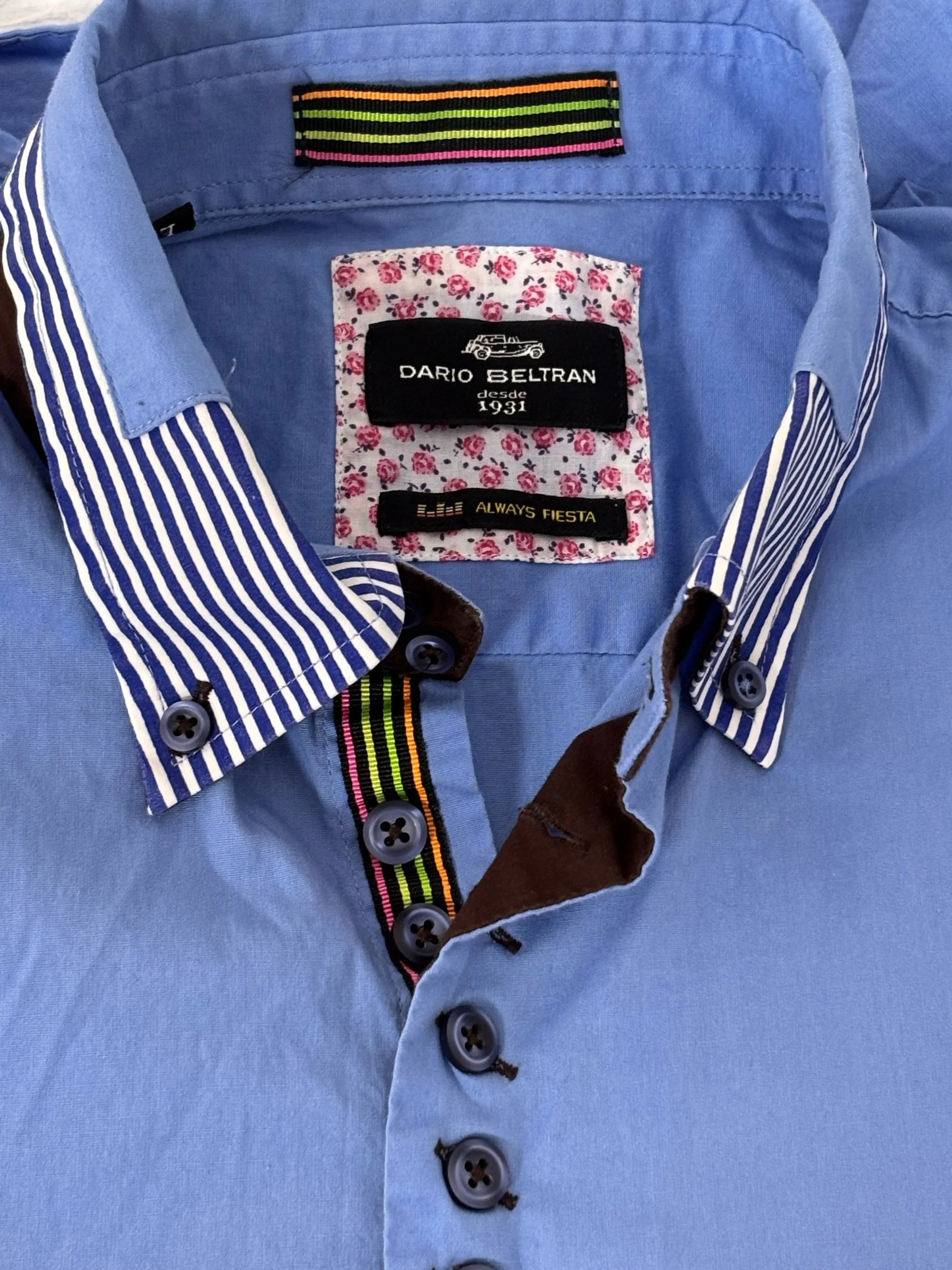 Close-up of the Dario Beltran men’s shirt showcasing the striped button-down collar, floral inner yoke, contrast brown trim, multicolor placket tape and premium branded details