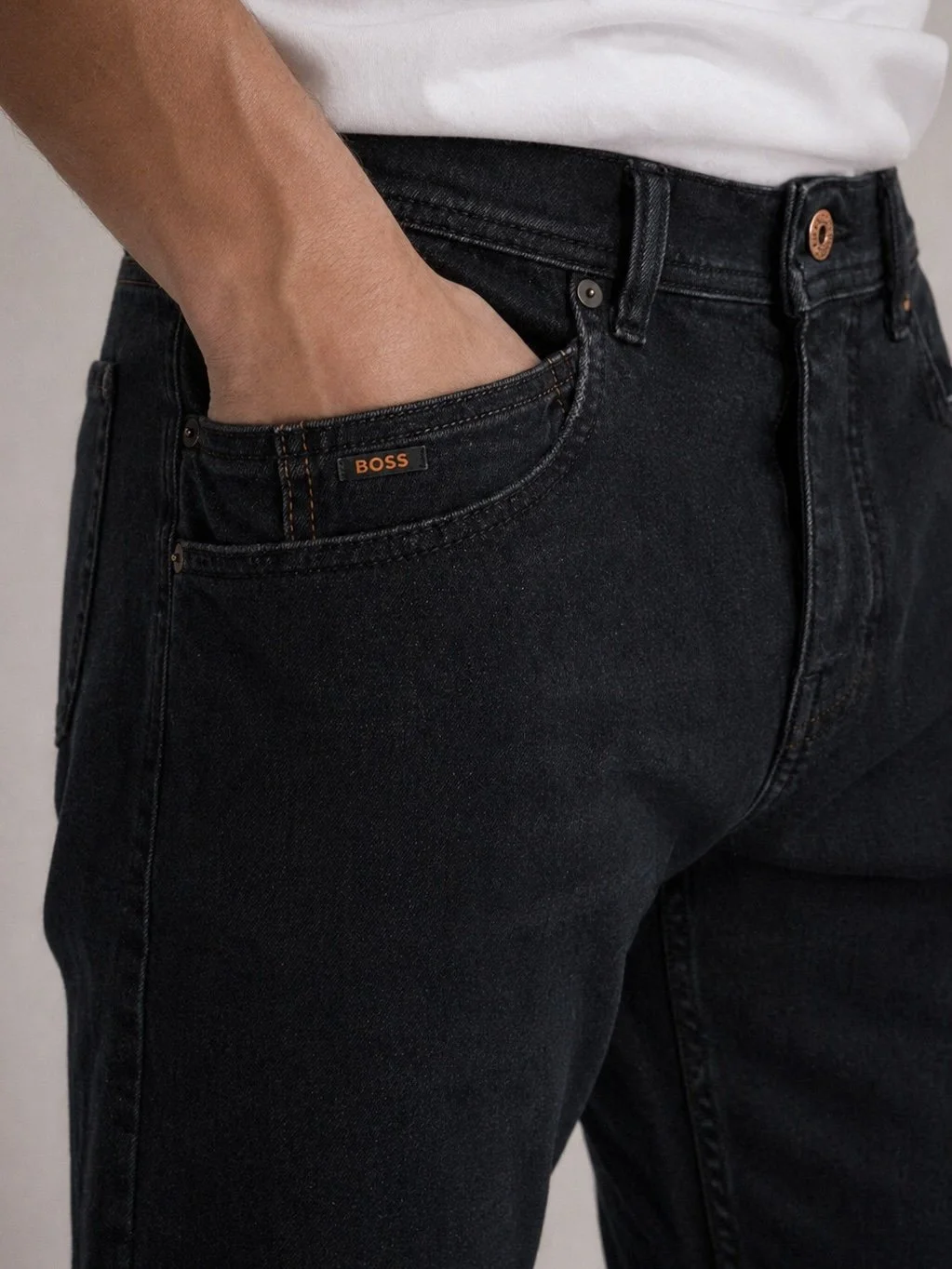 Close-up detail of BOSS dark blue men’s denim jeans with signature logo tab and premium washed cotton denim texture