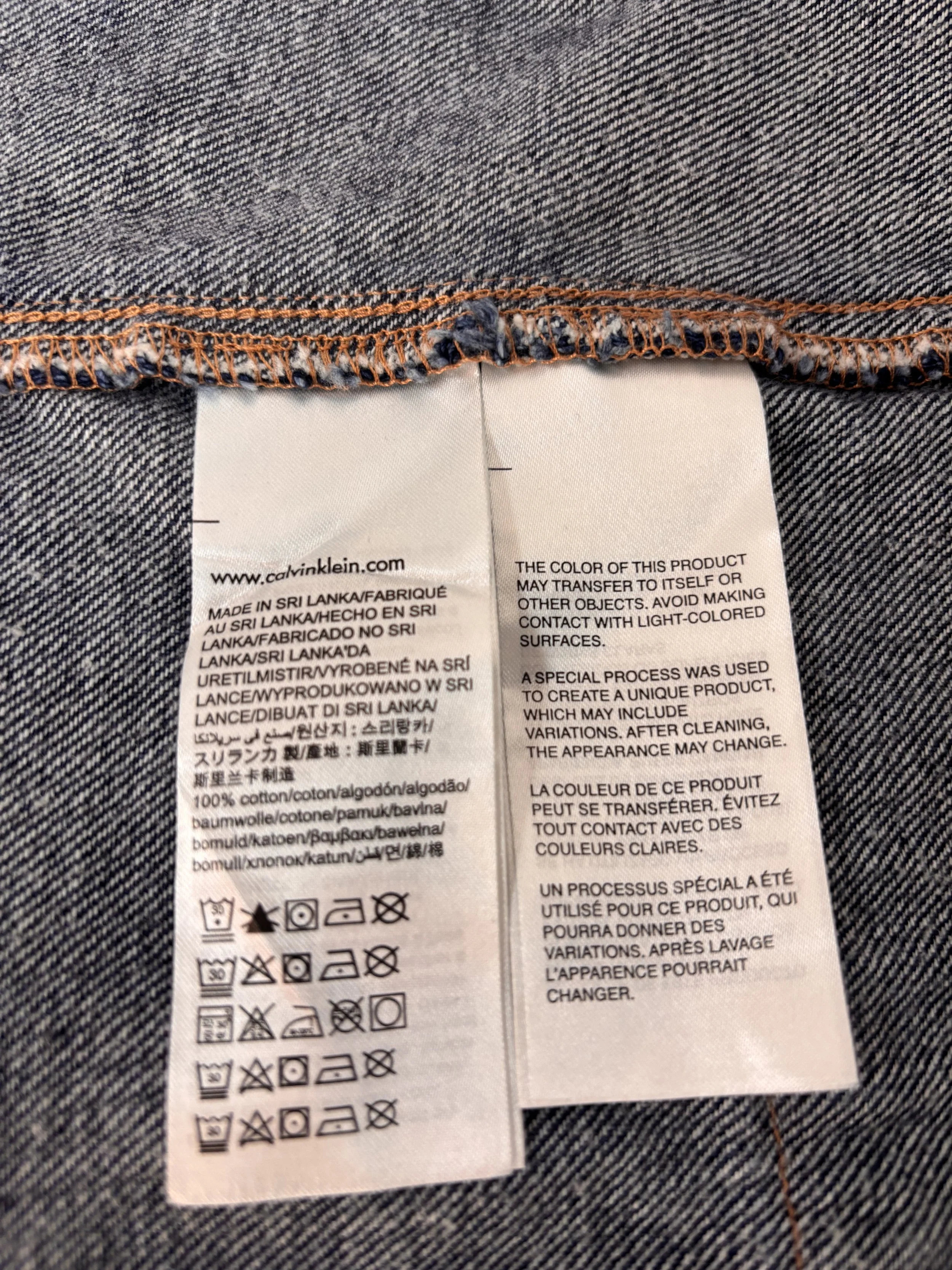 Calvin Klein Jeans dress care label showing 100% cotton fabric, size M and made in Sri Lanka.