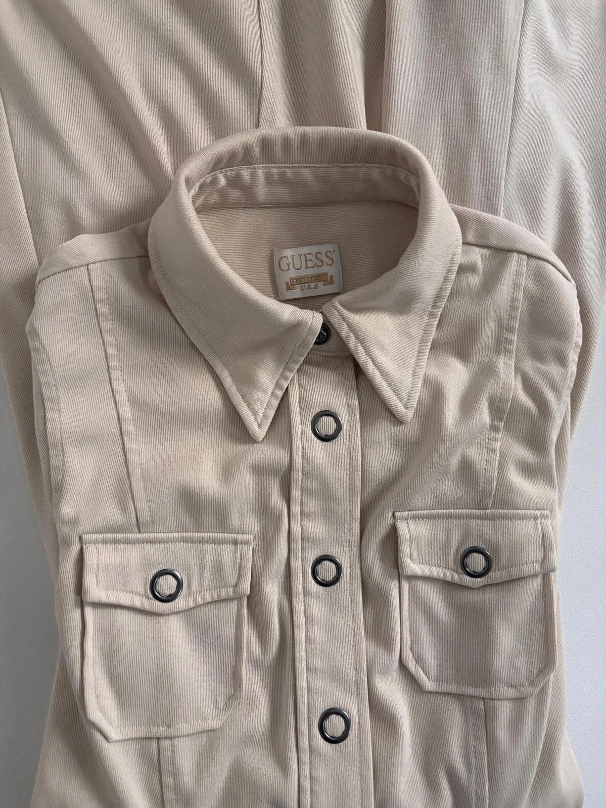 Close-up of Guess beige shirt dress fabric texture and metal button detail, structured cotton blend women’s designer dress