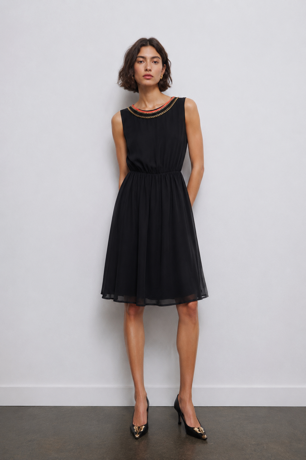 Silvian Heach black chiffon designer dress with gold chain neckline, sleeveless feminine dress on model