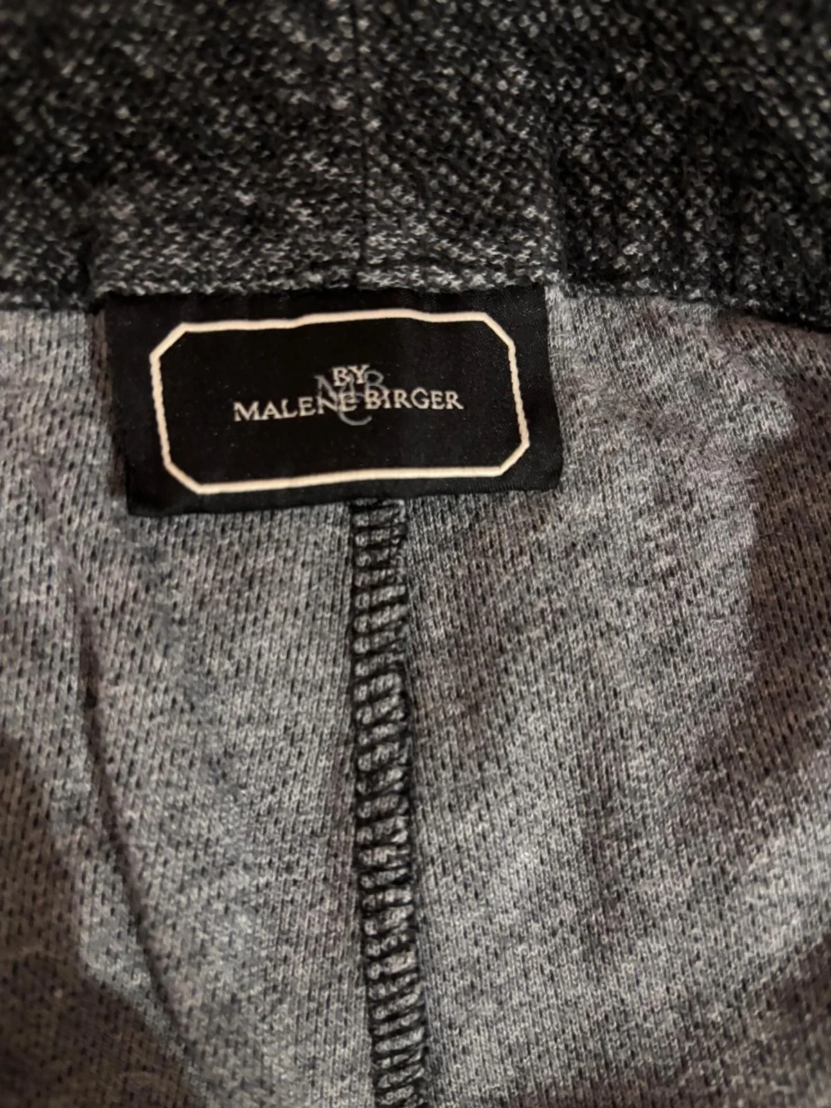 By Malene Birger brand label detail on luxury joggers, authentic designer clothing tag close-up