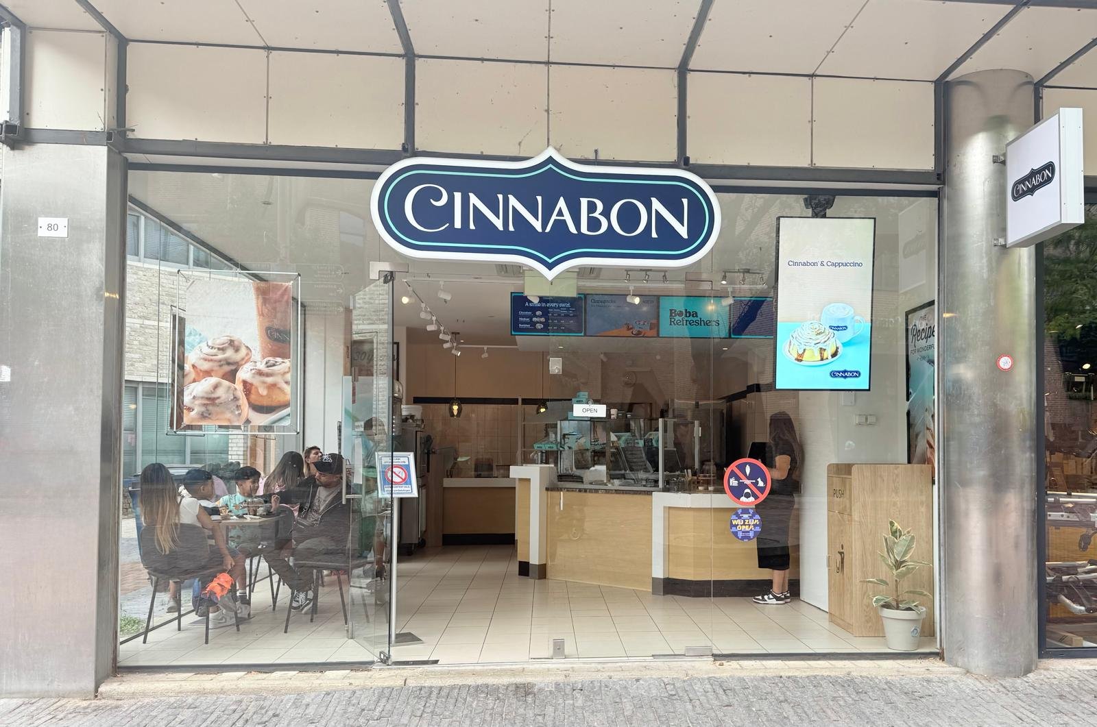 Cinnabon bakery storefront Amsterdamse Poort with seating area and digital menu screens inside
