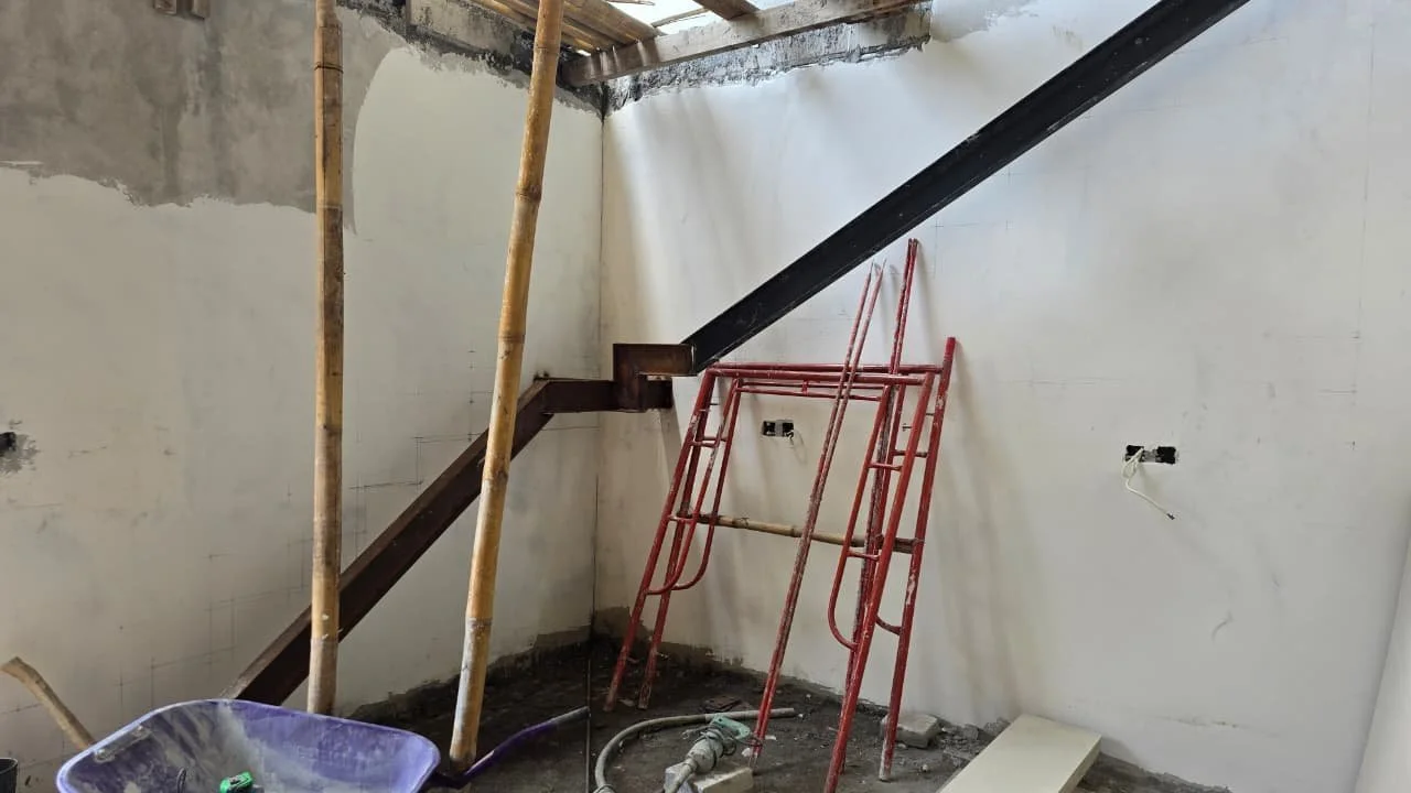 Construction site with scaffolding, electrical outlets, and a ladder leaning against a wall.