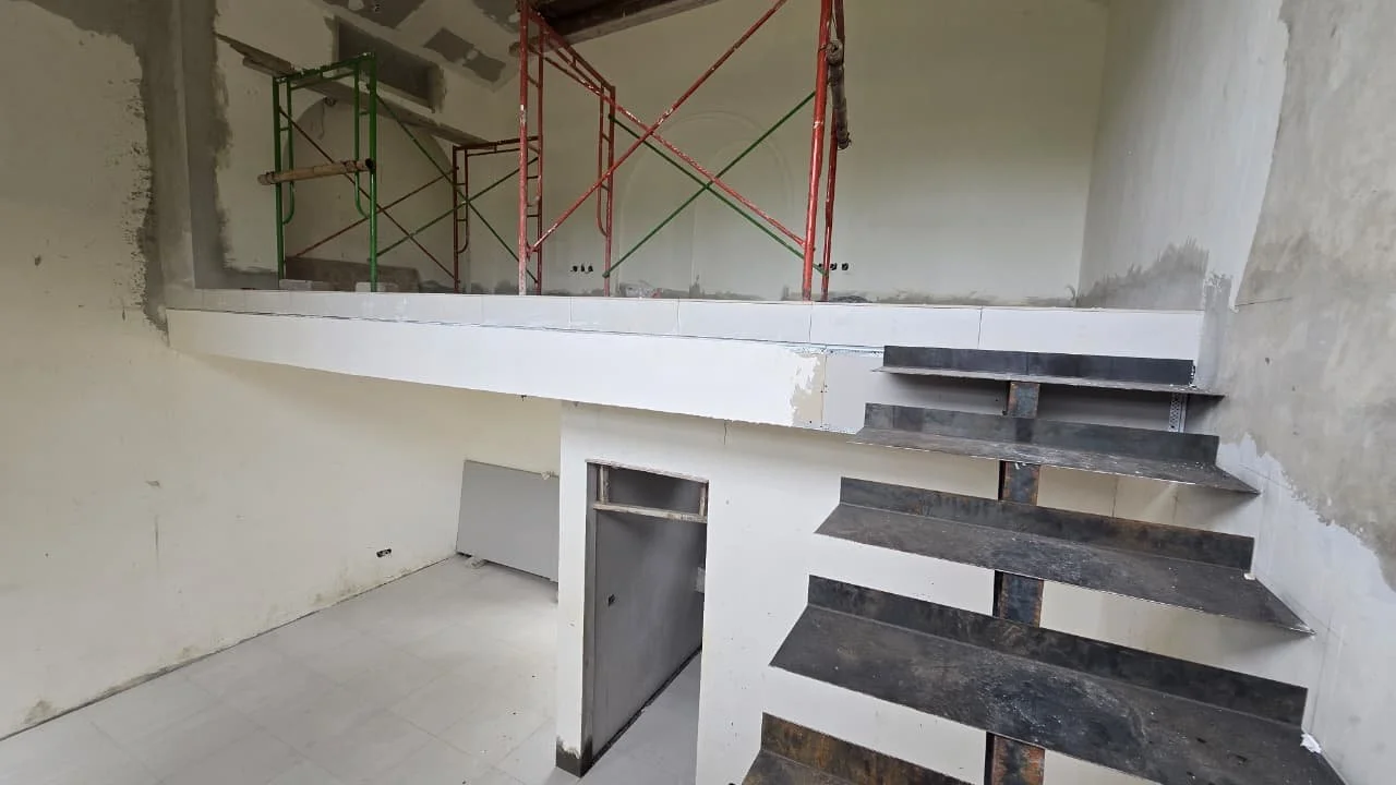 Construction site with unfinished stairs and scaffolding inside a building.