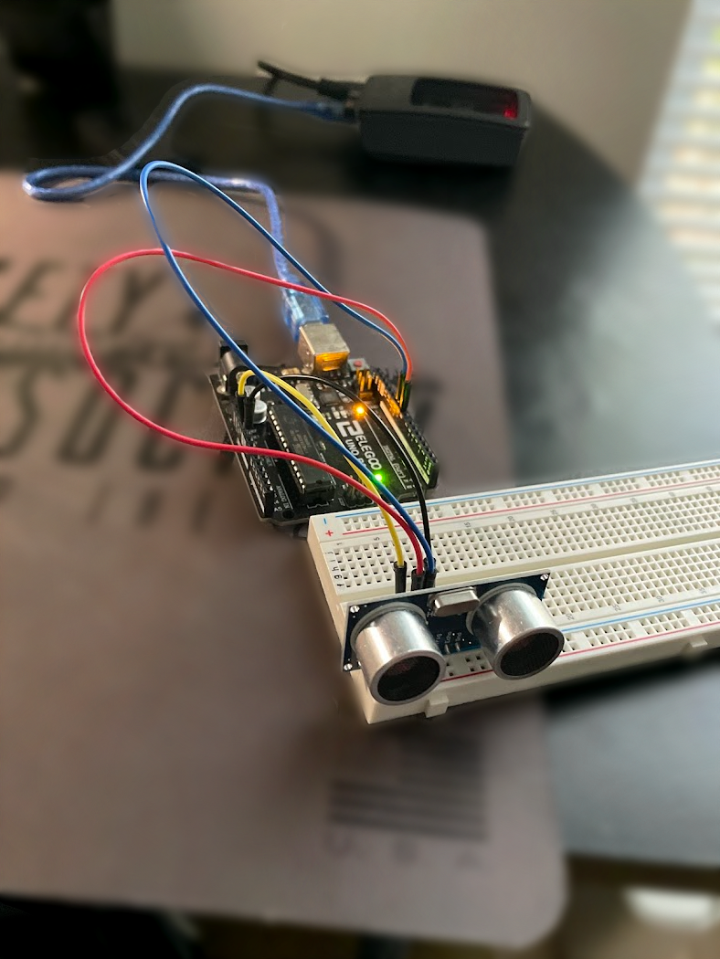 Diagram showing a Raspberry Pi powered ultrasonic sensor connected to an Arduino, with a computer monitor displaying a Python script for logging distance measurements. Red labels identify the Raspberry Pi, Arduino, ultrasonic sensor, and the initial test log, while a notification message indicates when the sensor detects a full trash can.