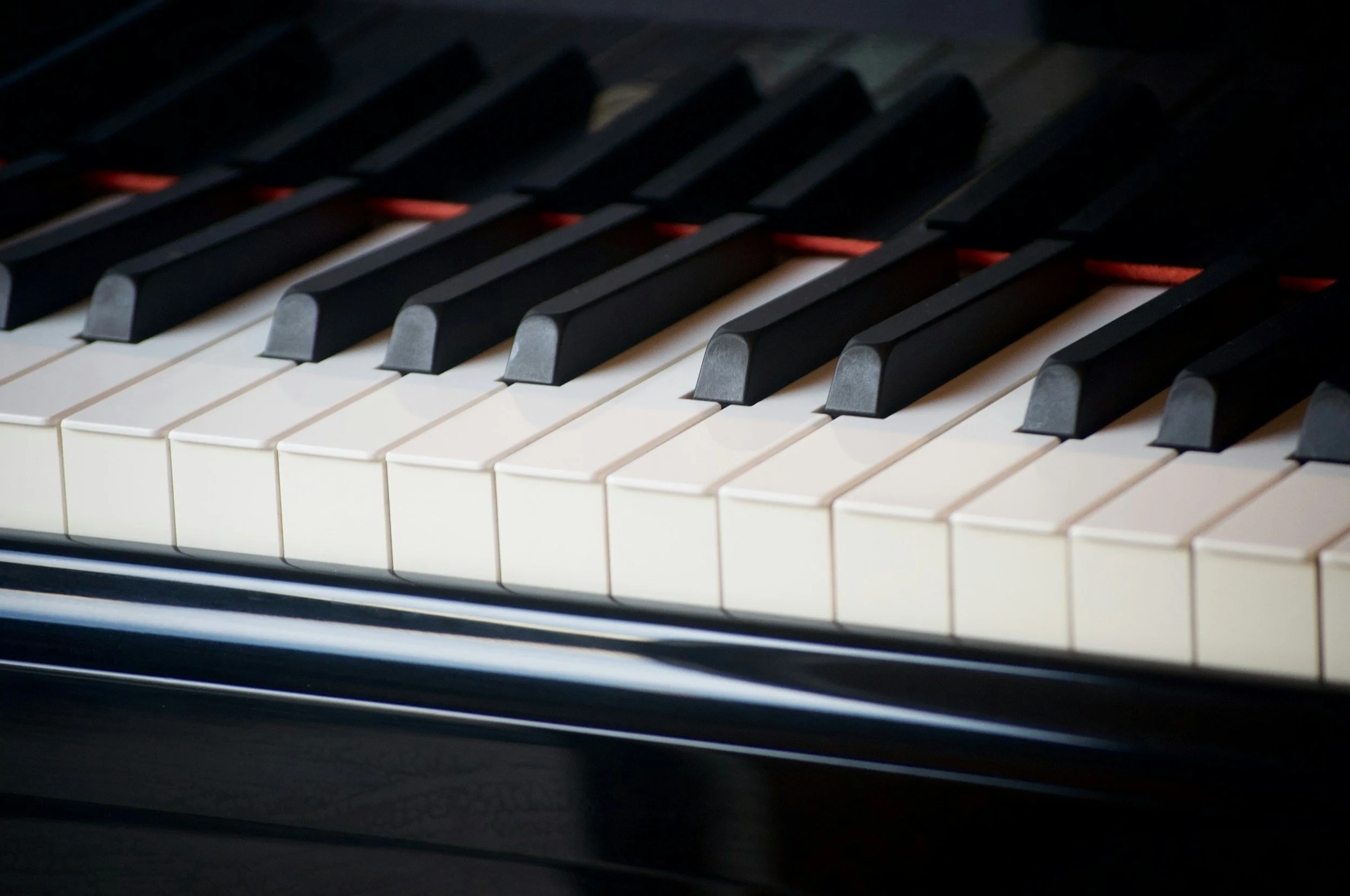 Close-up of piano keys with black and white keys arranged in a pattern, some keys illuminated in a dim setting.