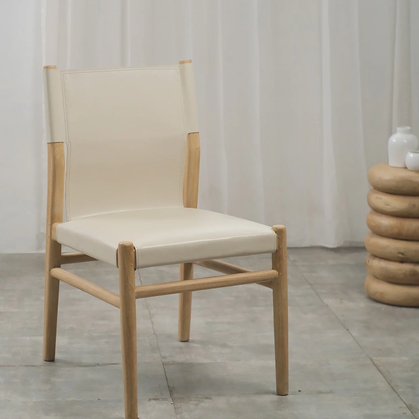 Estas sillas presentan un dise&ntilde;o contempor&aacute;neo y elegante, con estructura de madera de teka, reconocida por su durabilidad. El asiento y respaldo est&aacute;n tapizados en piel blanca, creando un contraste sutil y sofisticado con la mad