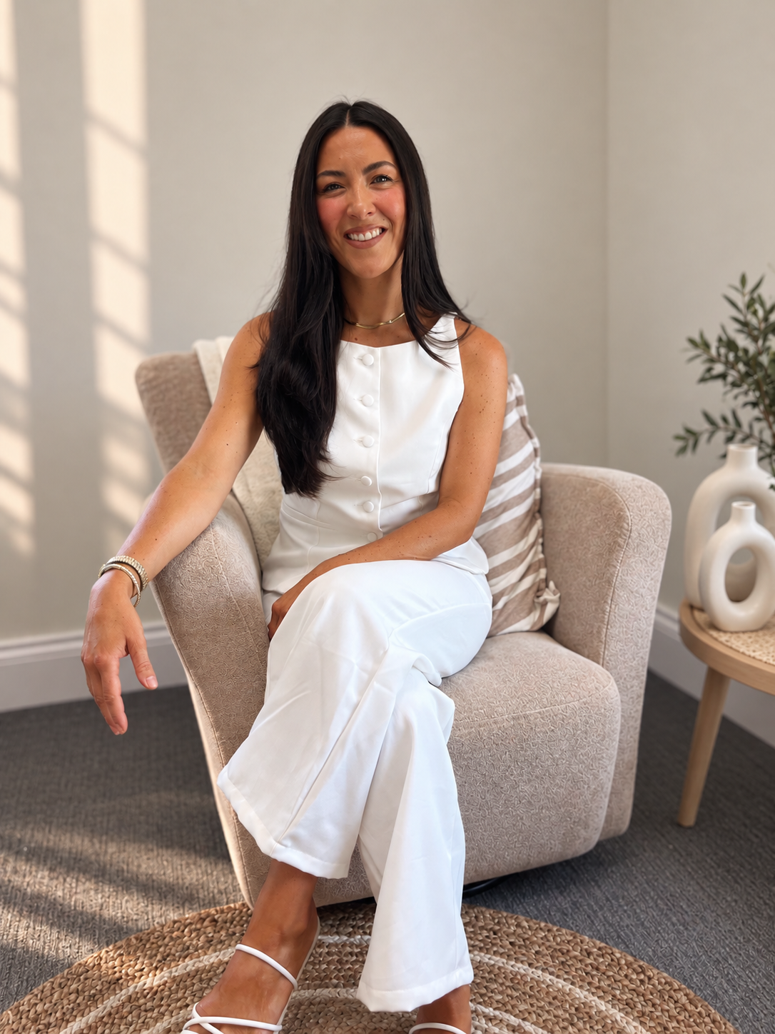 Portrait of a woman with long dark hair, smiling, wearing a black turtleneck against a plain white background.